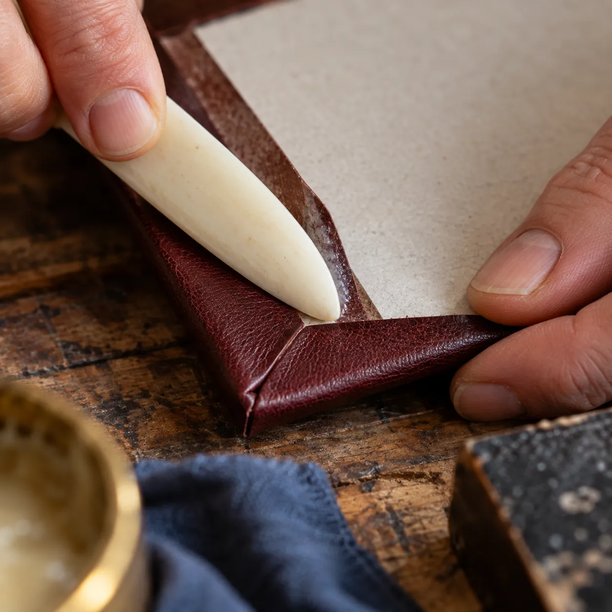 Pasted leather being folded over the corner of a book board
